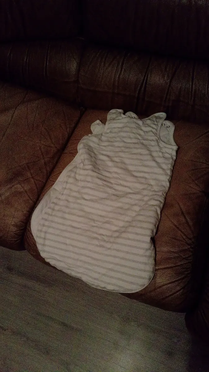 Striped baby sleeping bag laid on a leather sofa