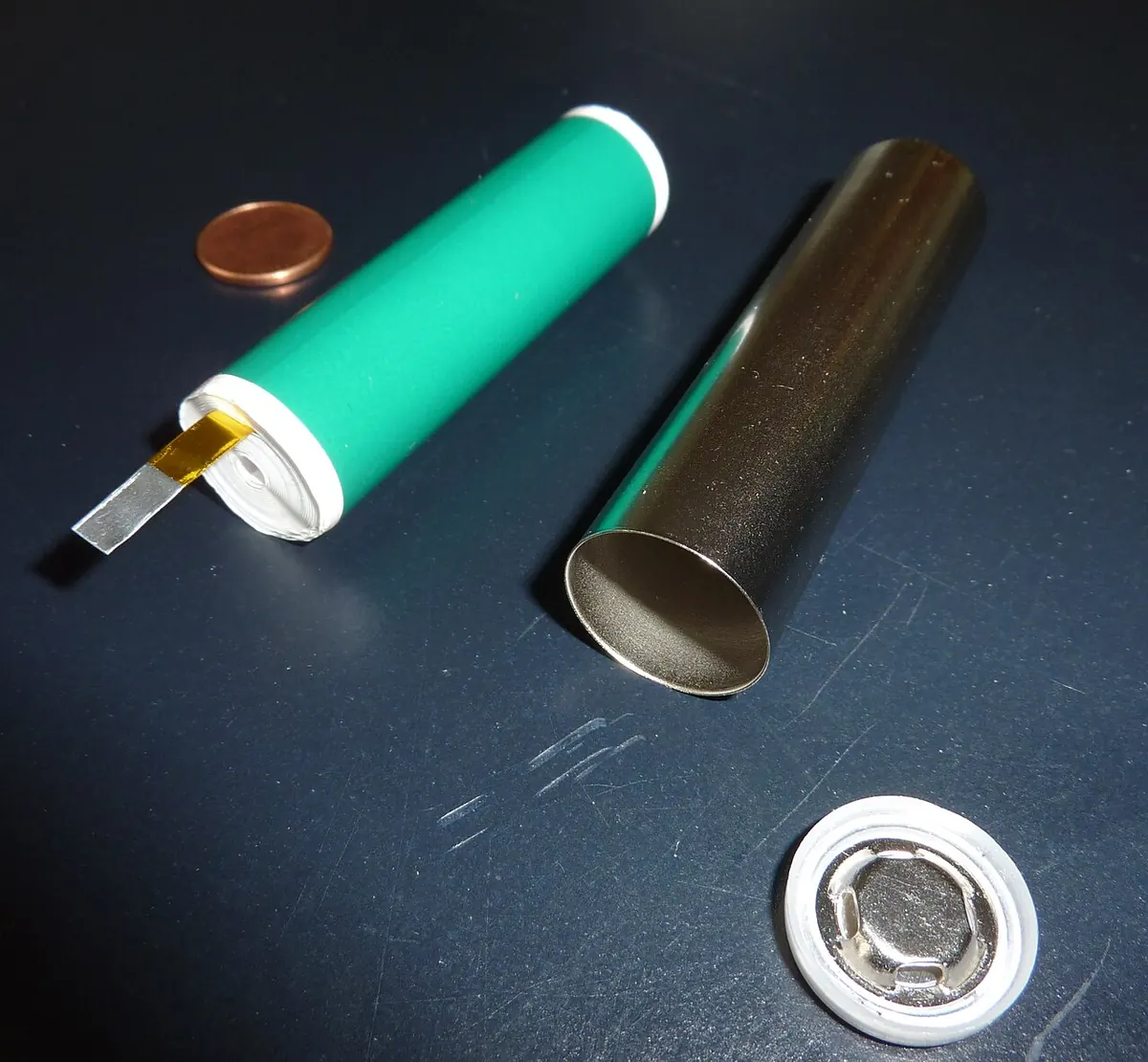 Cylindrical lithium ion cell taken apart beside a small coin