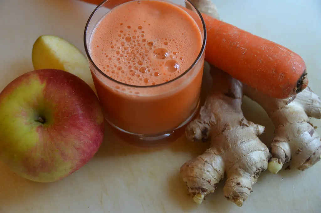 Glass of fresh carrot juice with an apple, carrot and ginger
