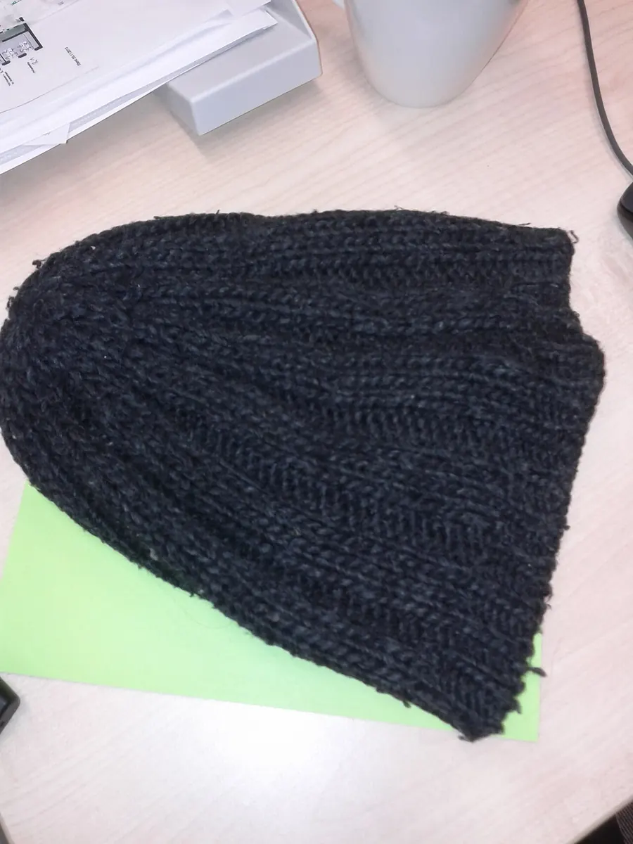 Dark grey ribbed wool beanie laid flat on a desk