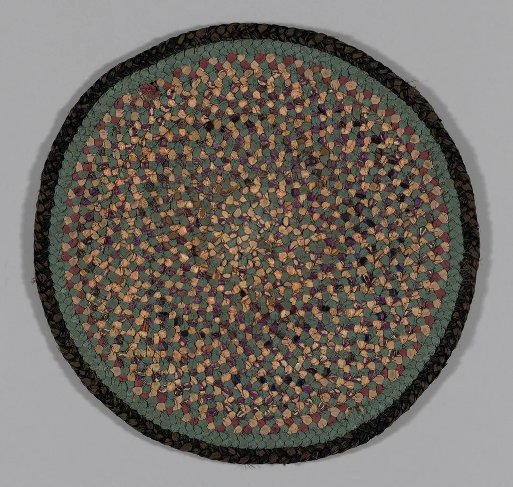 Round braided rug in green and peach with a dark border