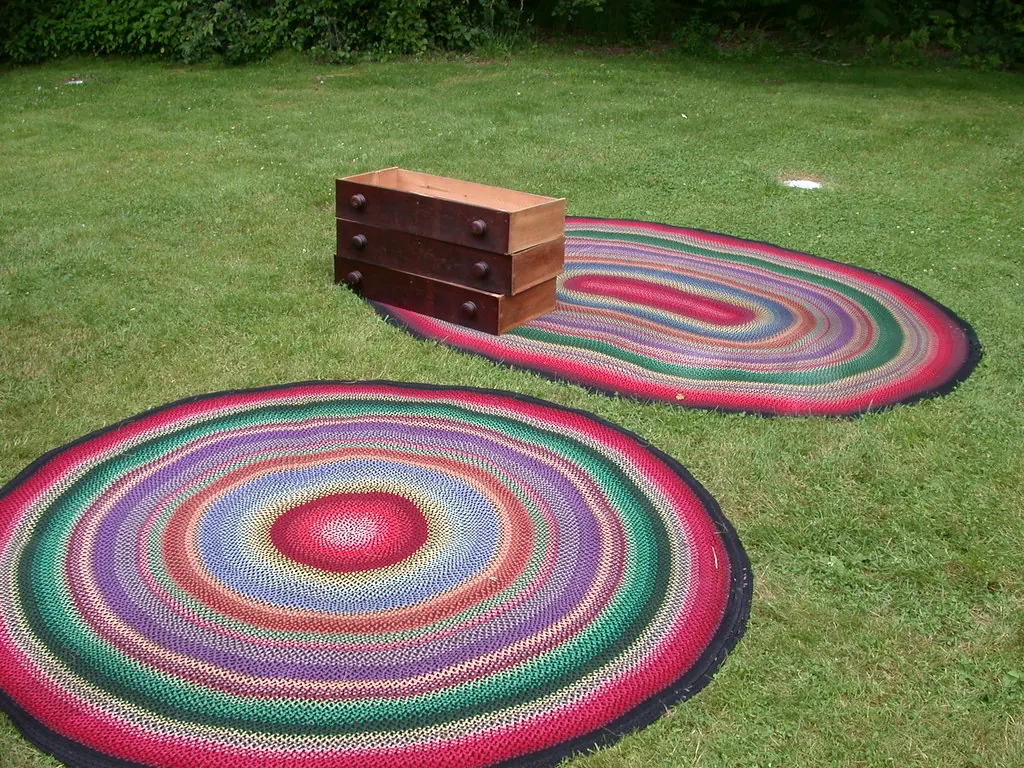 Round and oval braided rugs laid out on a lawn