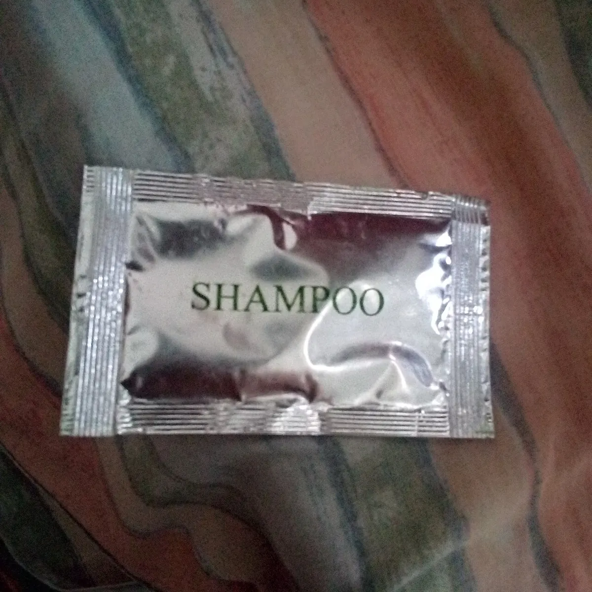 Foil sachet of shampoo on a patterned cloth