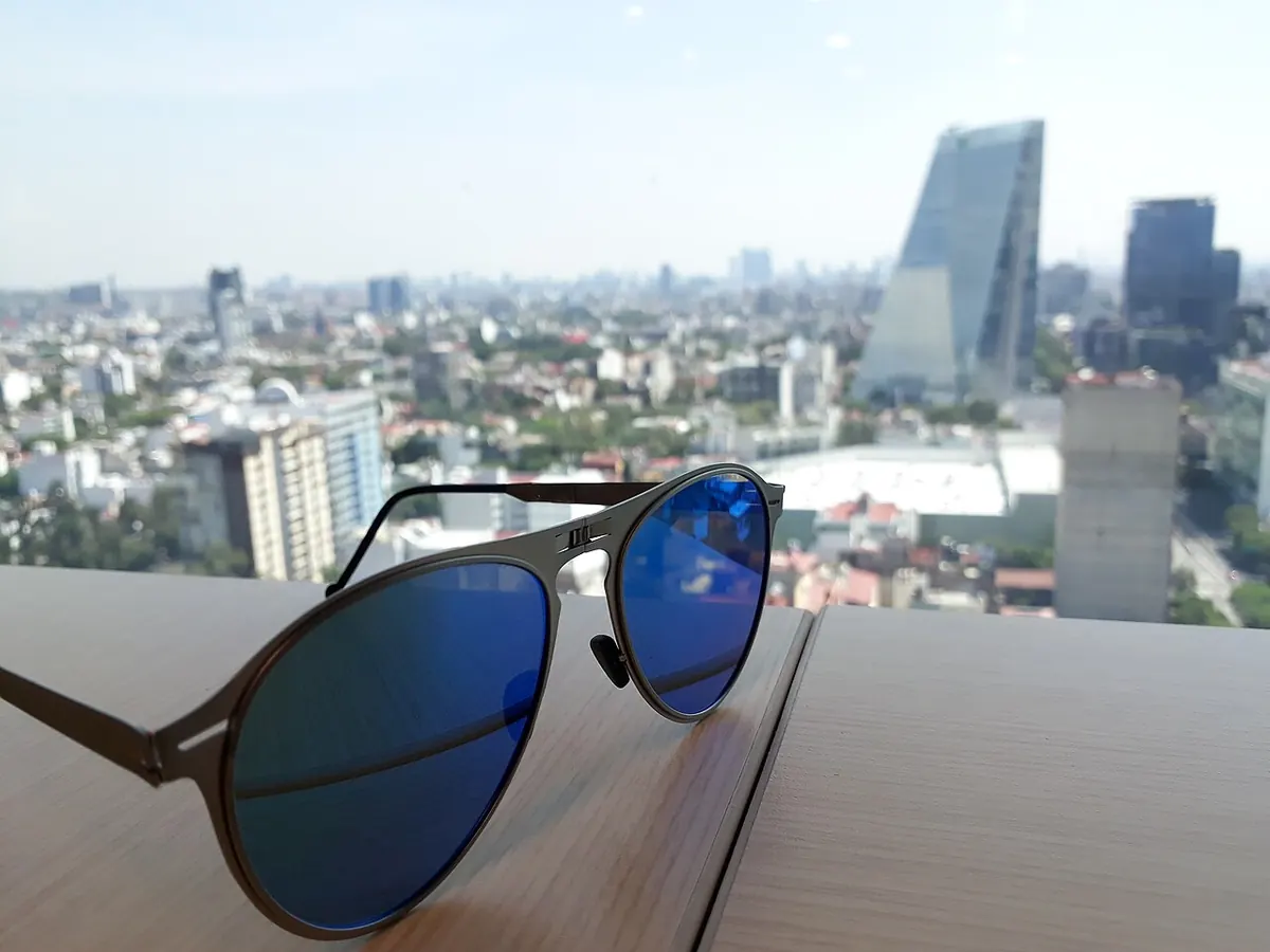 Aviator sunglasses with blue mirrored lenses above a city view