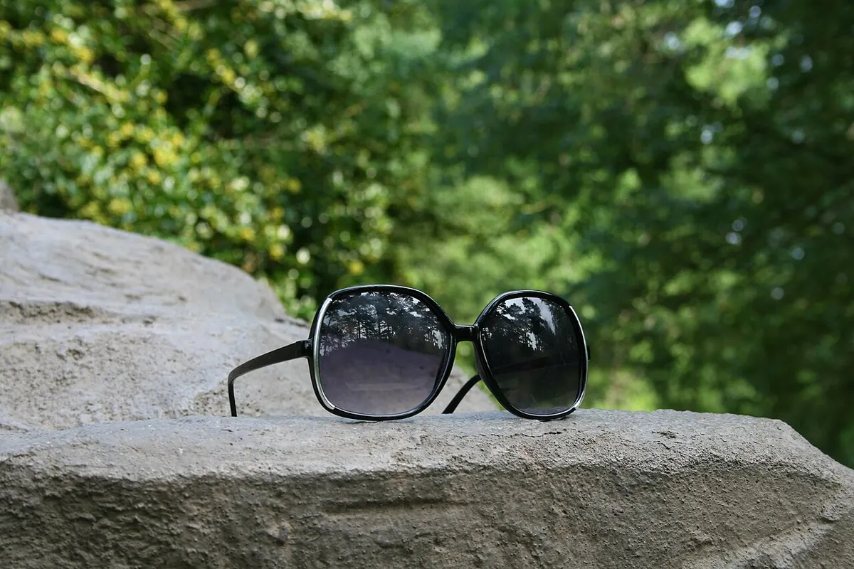 Large black sunglasses resting on a stone ledge outdoors