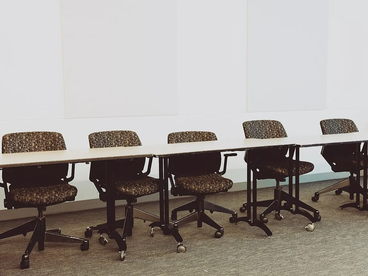 Row of swivel office chairs along a long white table
