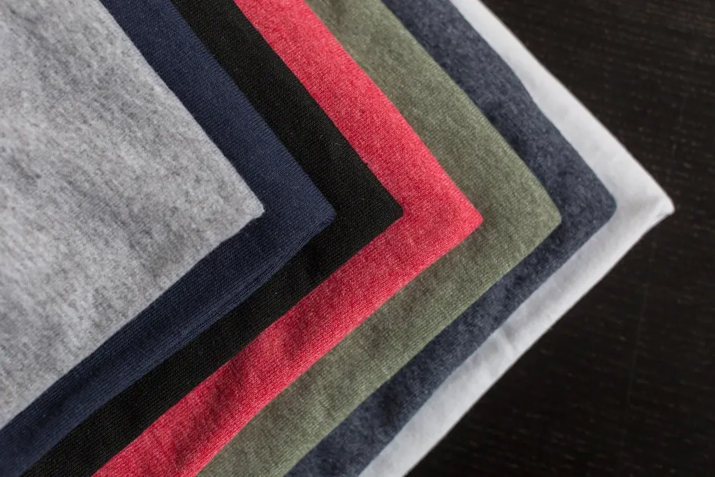 Folded T-shirts in grey, red, navy and olive stacked neatly