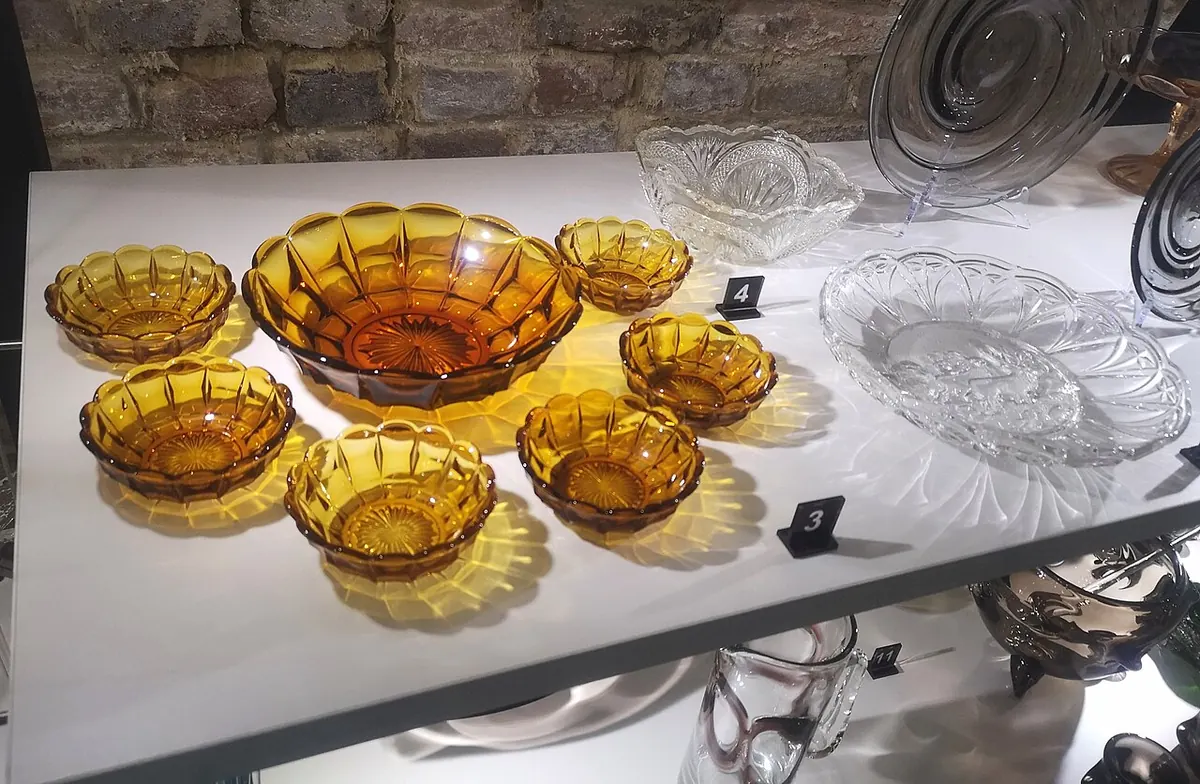 Amber pressed glass bowls and clear glass dishes on a shelf