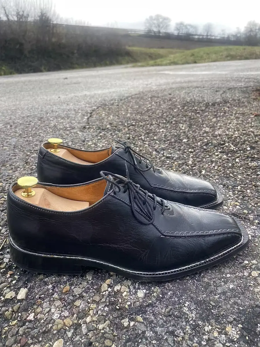 Black leather lace up shoes with shoe trees on gravel