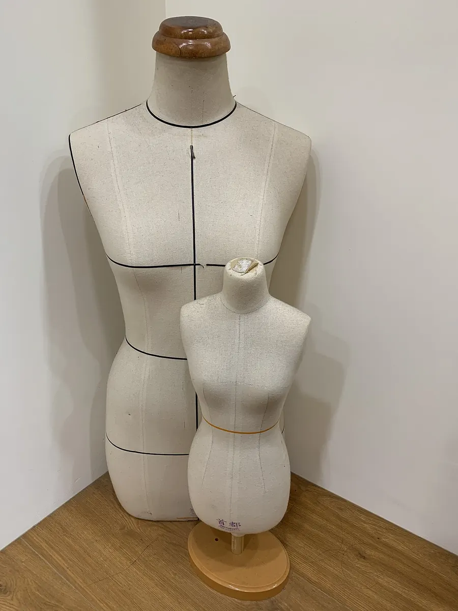 Two linen dress forms of different sizes in a room corner