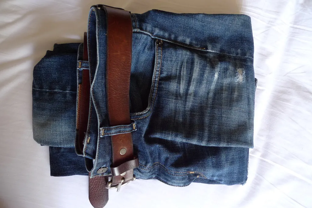Folded dark blue jeans with a brown leather belt