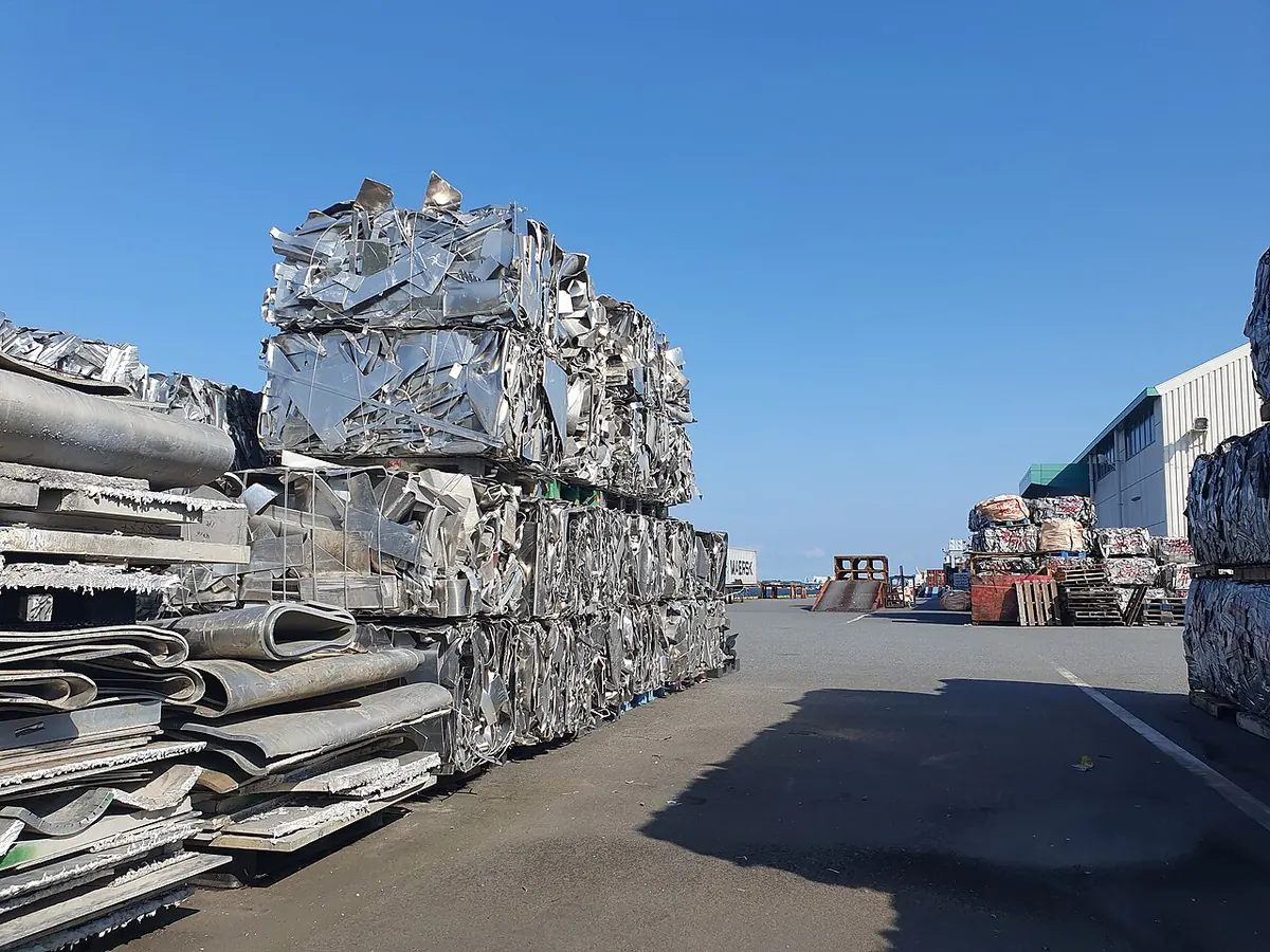 Baled metal scrap stacked on a pier under blue sky