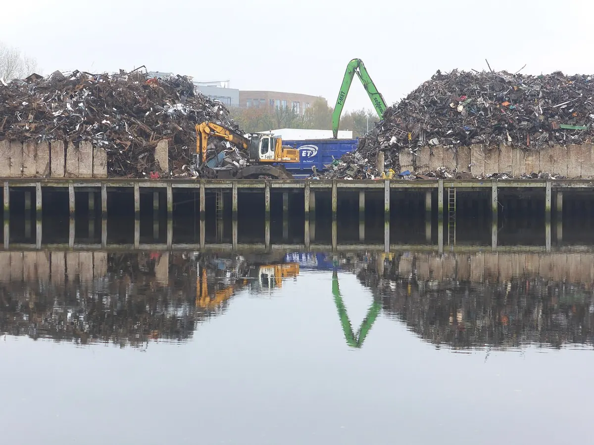 Large piles of scrap metal at a harbour yard by water