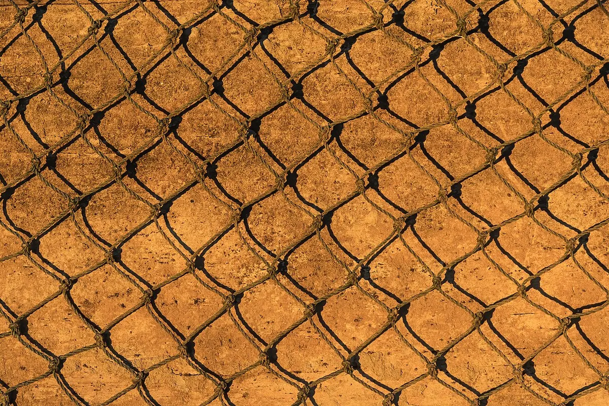 Knotted fishing net mesh over a wooden board