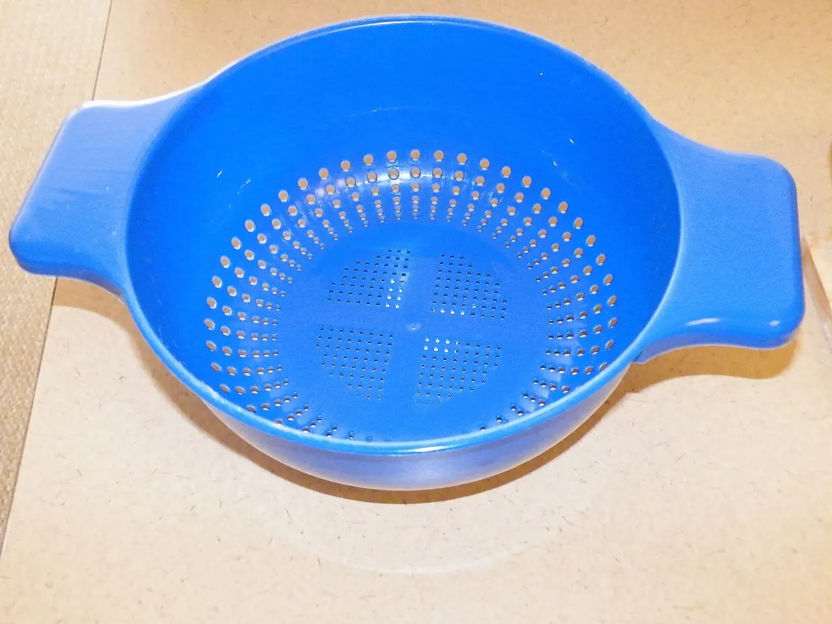 Blue plastic colander with two handles on a worktop