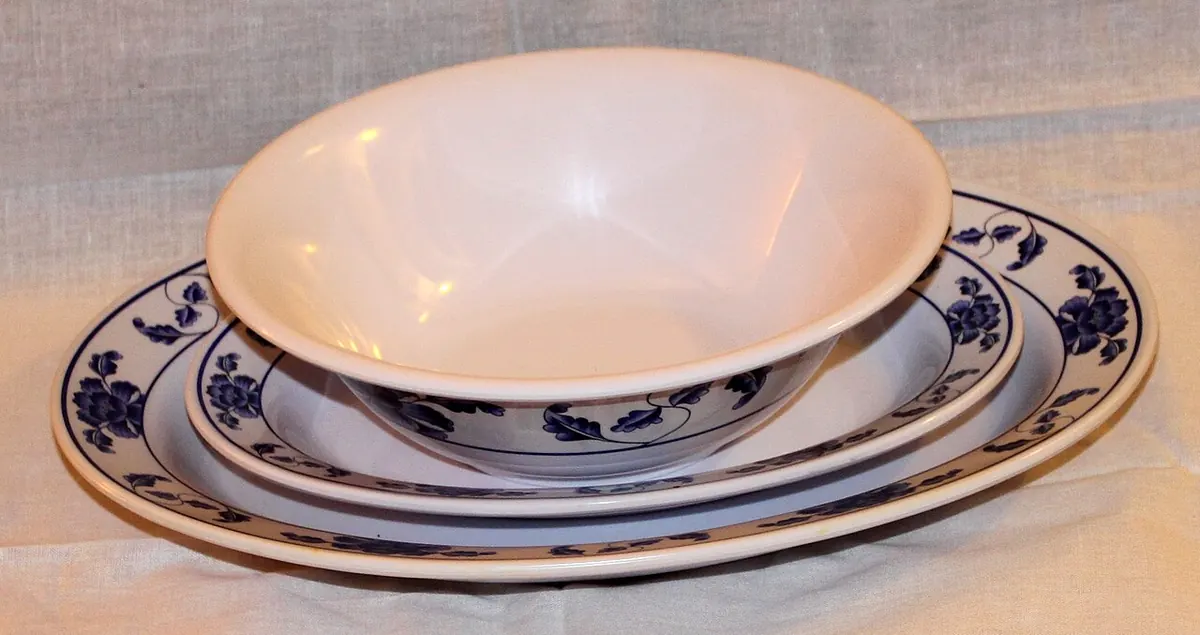 Stacked melamine plates and a bowl with a blue floral rim