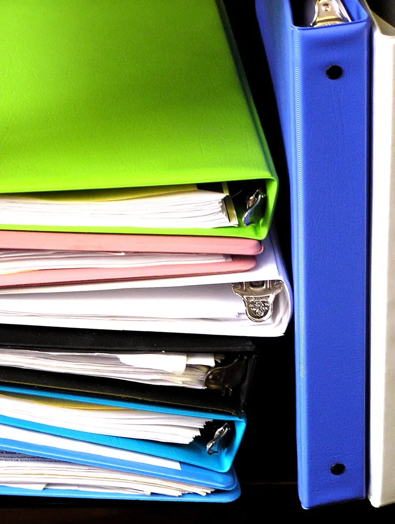 Stack of colourful ring binders filled with loose papers