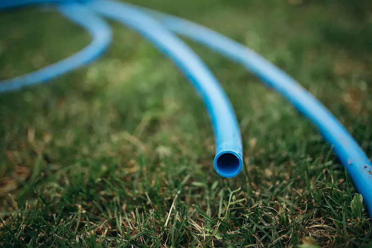 Blue rubber hose lying on green grass