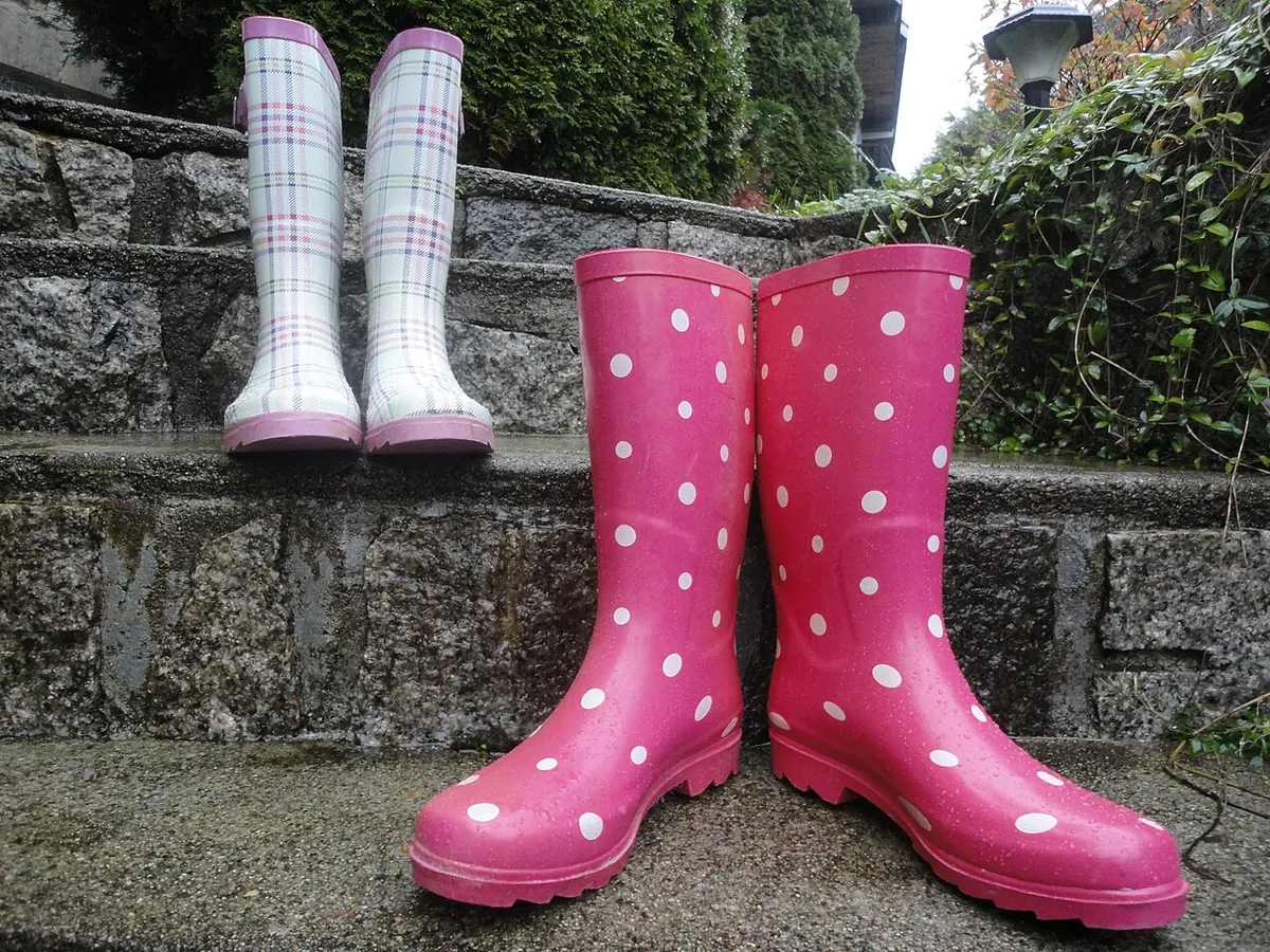Pink polka dot rain boots and a checked pair on stone steps