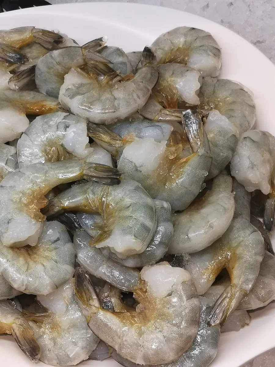 Raw headless tiger shrimp with shells on in a bowl