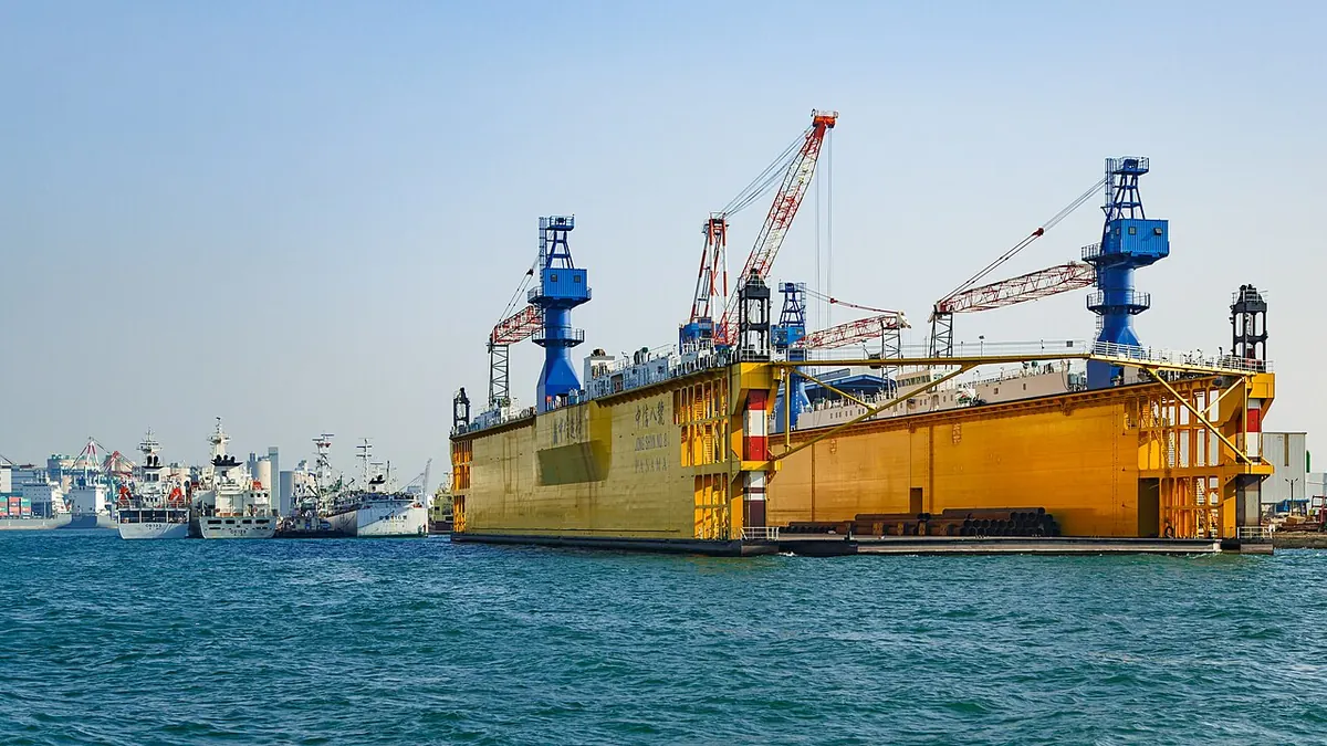 Yellow floating dry dock with cranes in a harbour