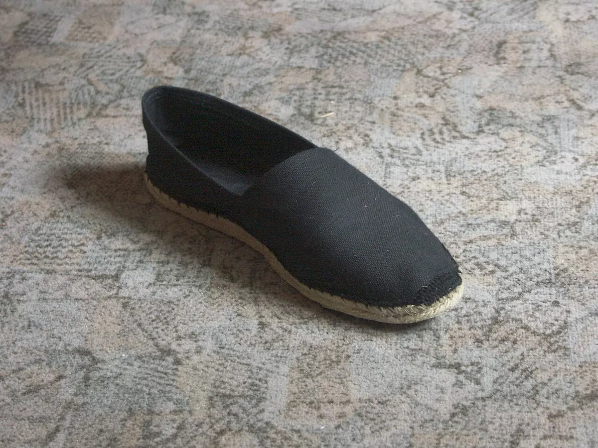 Black canvas espadrille with a jute sole on a carpet