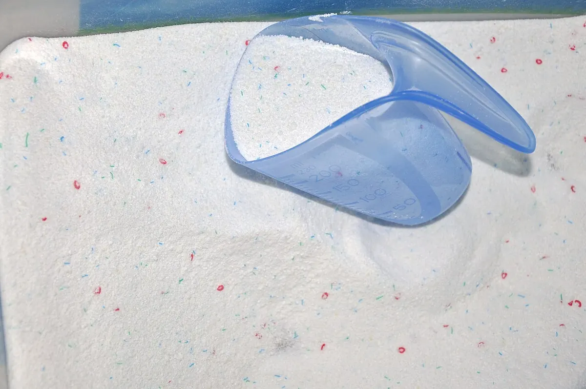 Laundry detergent powder with a blue plastic scoop