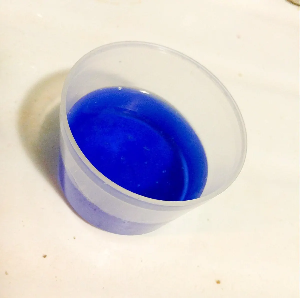 Blue liquid laundry detergent in a clear measuring cup