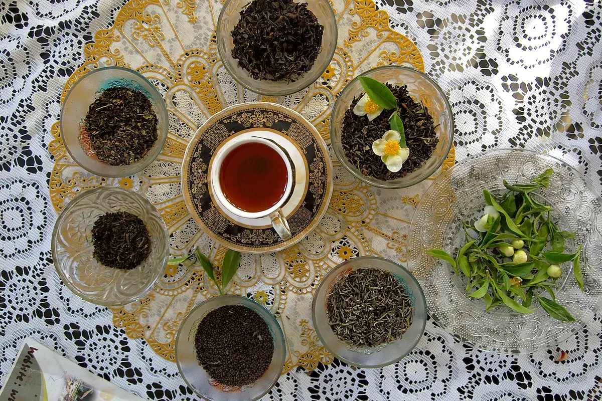 Bowls of dry black tea leaves around a cup of tea