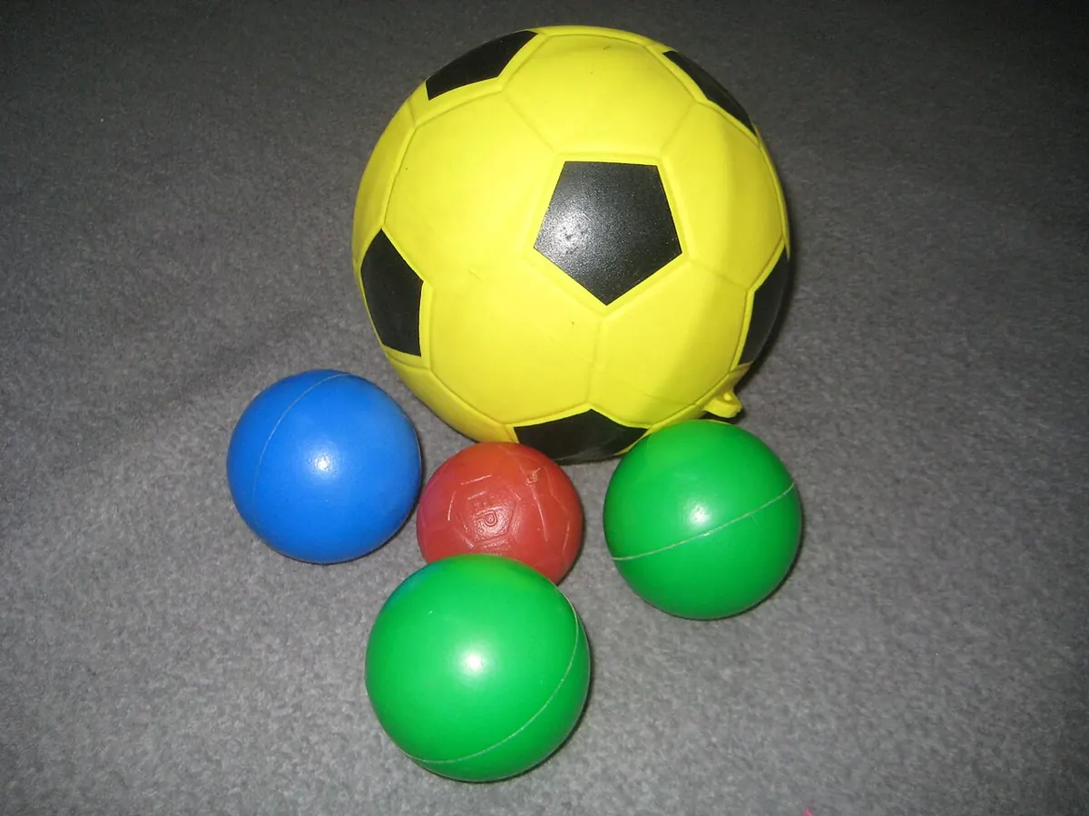 Yellow plastic football with smaller coloured balls on a carpet