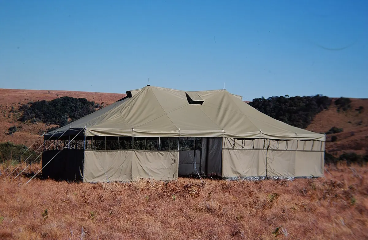 Large canvas shelter tent in an open grassy field
