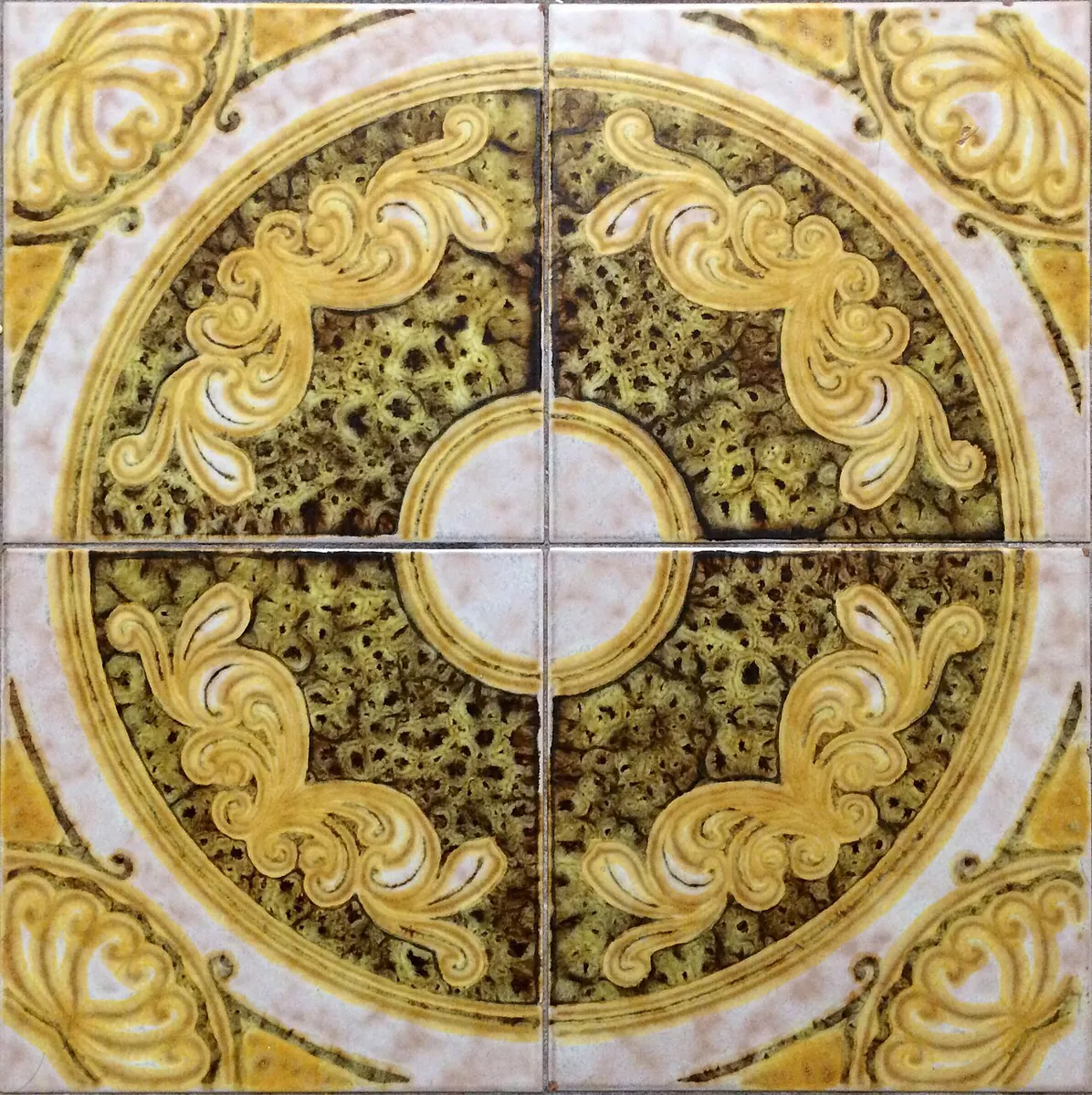 Four glazed floor tiles forming a yellow floral medallion