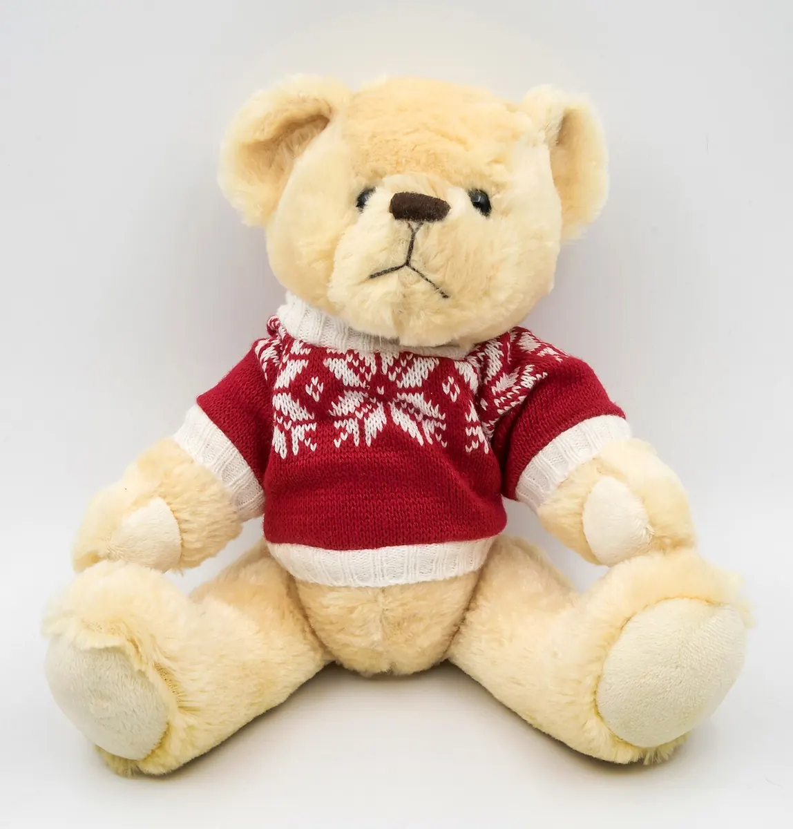 Teddy bear in a red knitted jumper on a white background