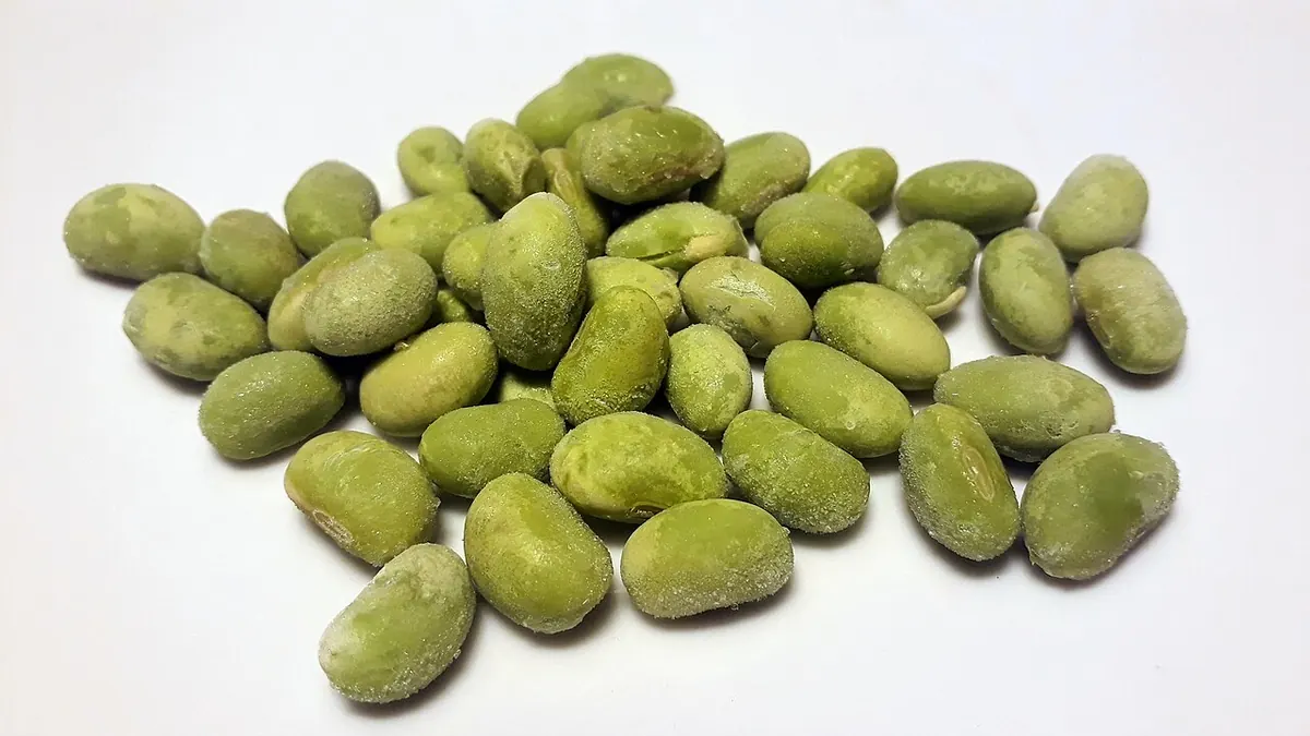 Frozen green soybeans with frost on a white surface