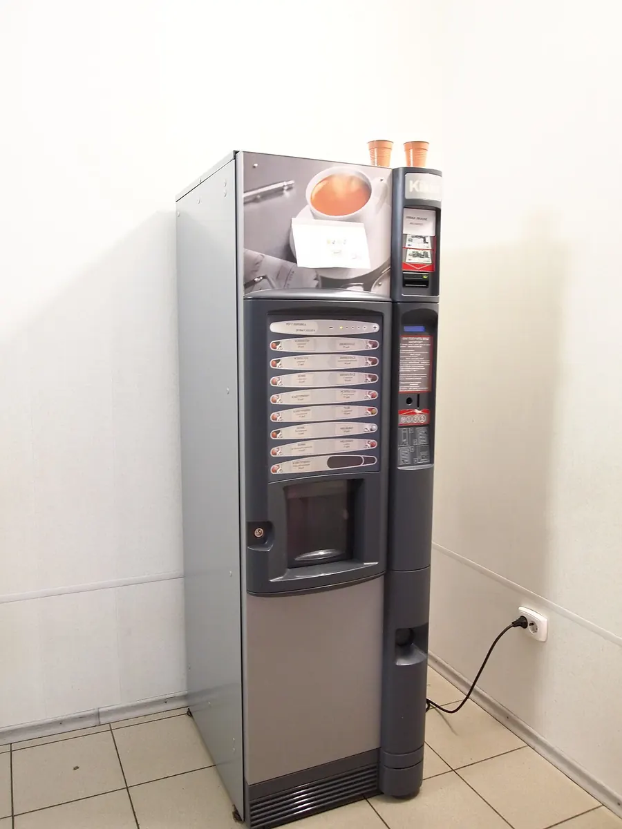 Coffee vending machine standing in a white corridor