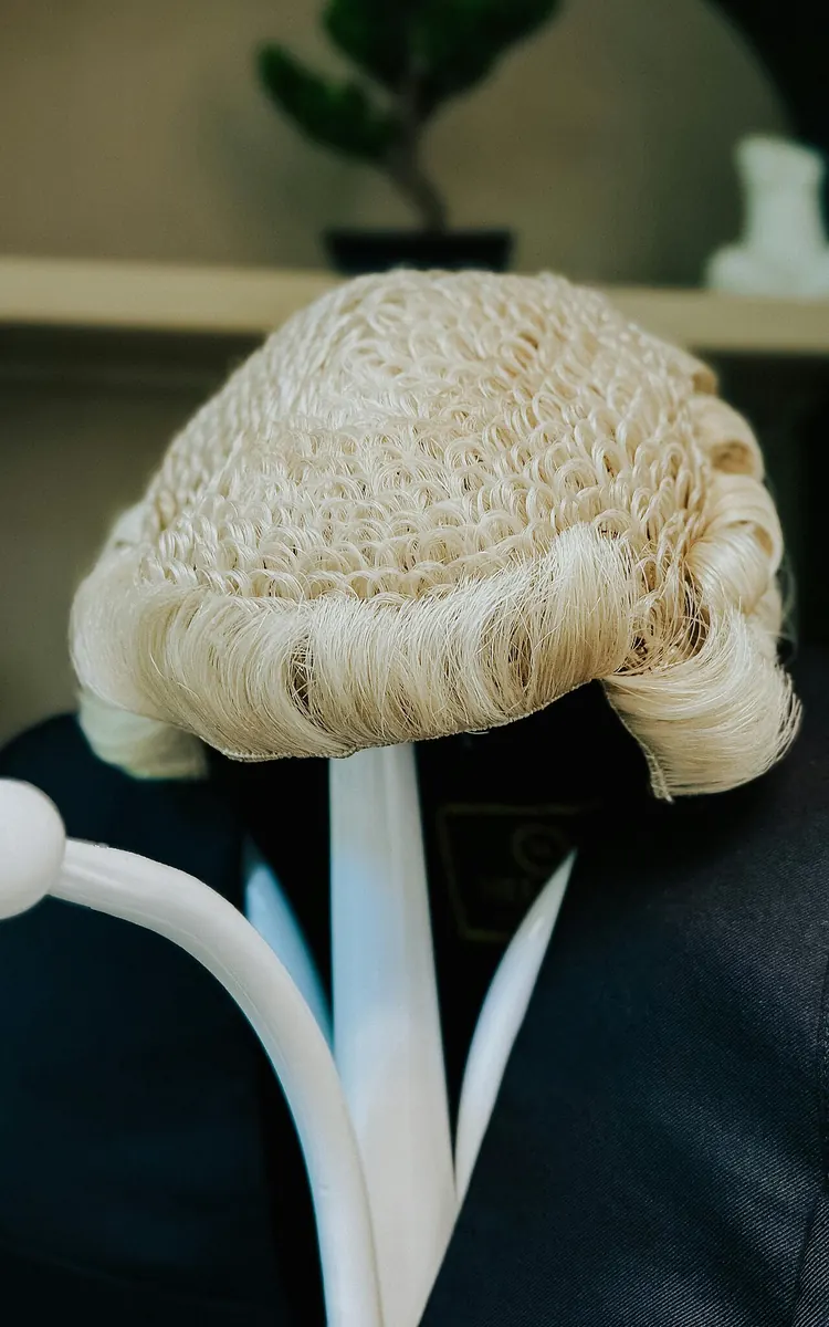 White curled barrister wig on a display stand